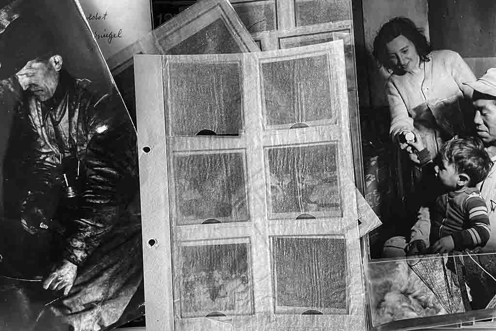 Ein Schwarz-Weiß-Foto zeigt eine Nahaufnahme einer Sammlung von Fotos und Negativen aus dem Archiv Bock-Schroeder, die in einer Archivmappe aufbewahrt werden.