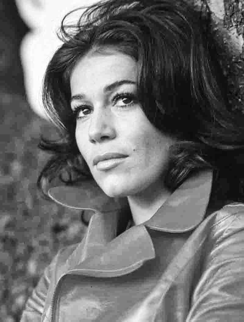 Schwarz-Weiß-Porträt der Schauspielerin Hannelore Elsner, aufgenommen von der Fotografin Ingeborg Bock-Schroeder. Die Aufnahme zeigt die Schauspielerin in einer Nahaufnahme mit dunklem, voluminösem Haar und einem markanten Kragen, wobei ihr Blick nachdenklich in die Ferne gerichtet ist.